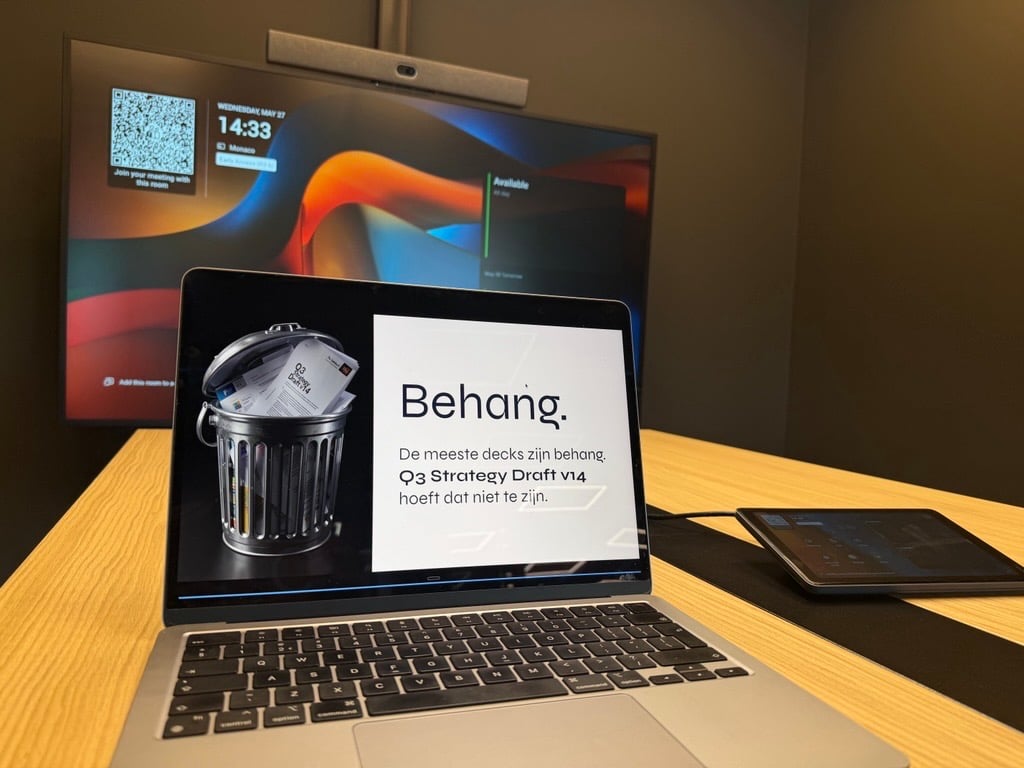 Vier collega's in een vergaderruimte, ieder gefocust op het eigen laptopscherm met een AI-gegenereerde presentatie