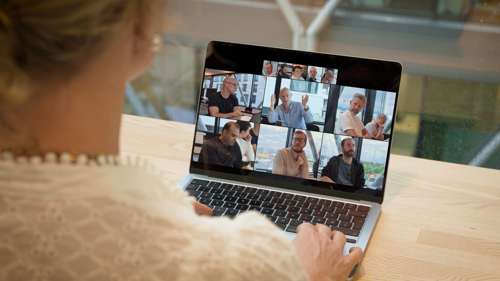 Remote deelnemer ziet een grote vergaderzaal waarin de actieve sprekers groter in beeld staan dan de rest van de tafel