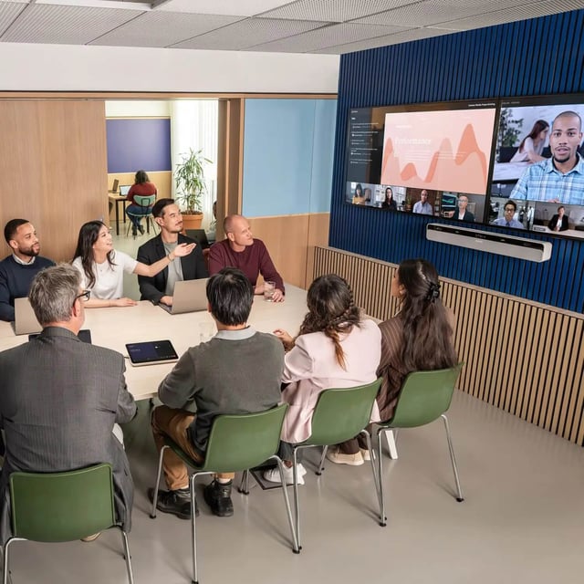 Zwarte Shure IntelliMix Bar Pro videobar onder een scherm in een grotere vergaderruimte
